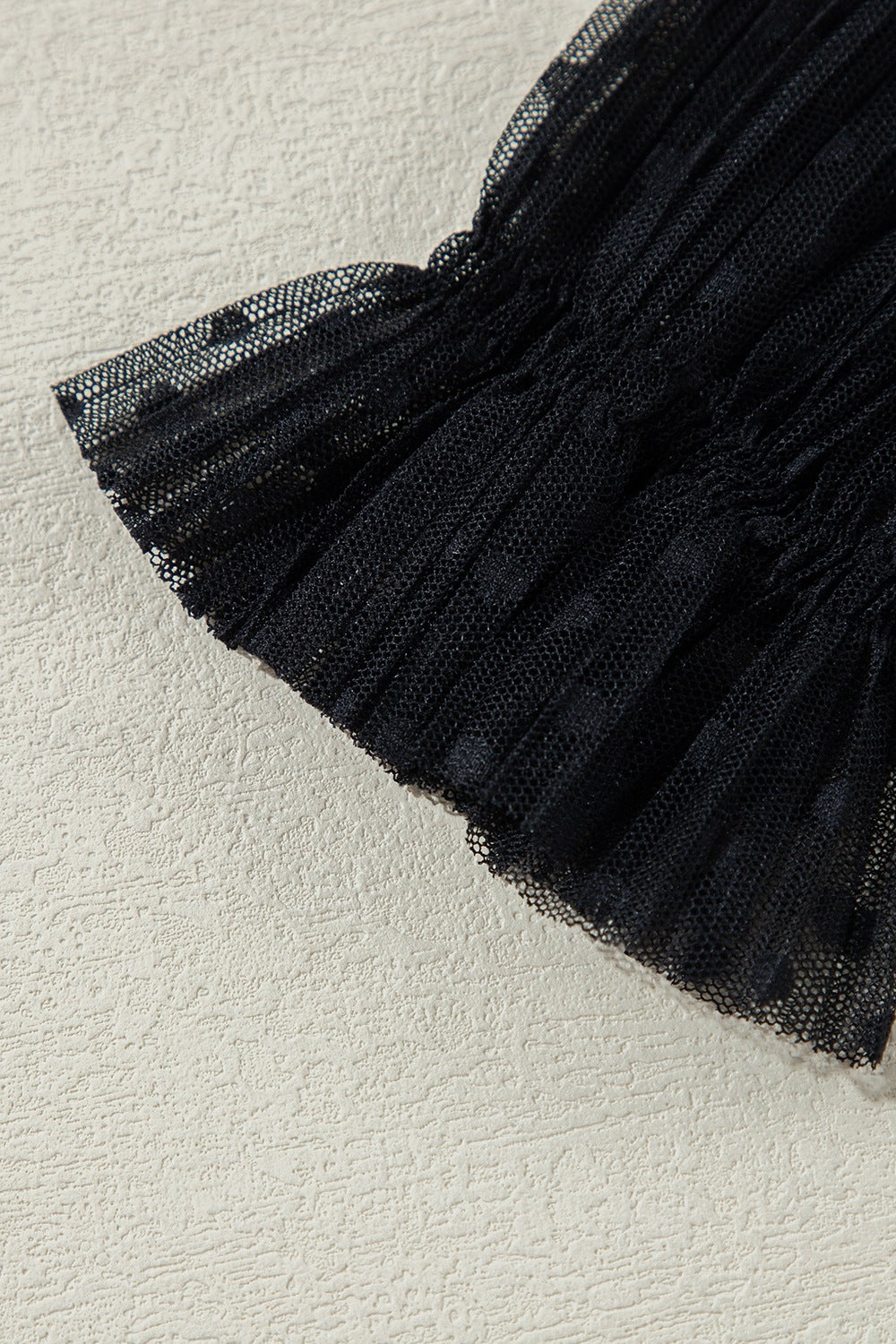Black sheer mesh blouse with textured dot pattern and ruched detail.