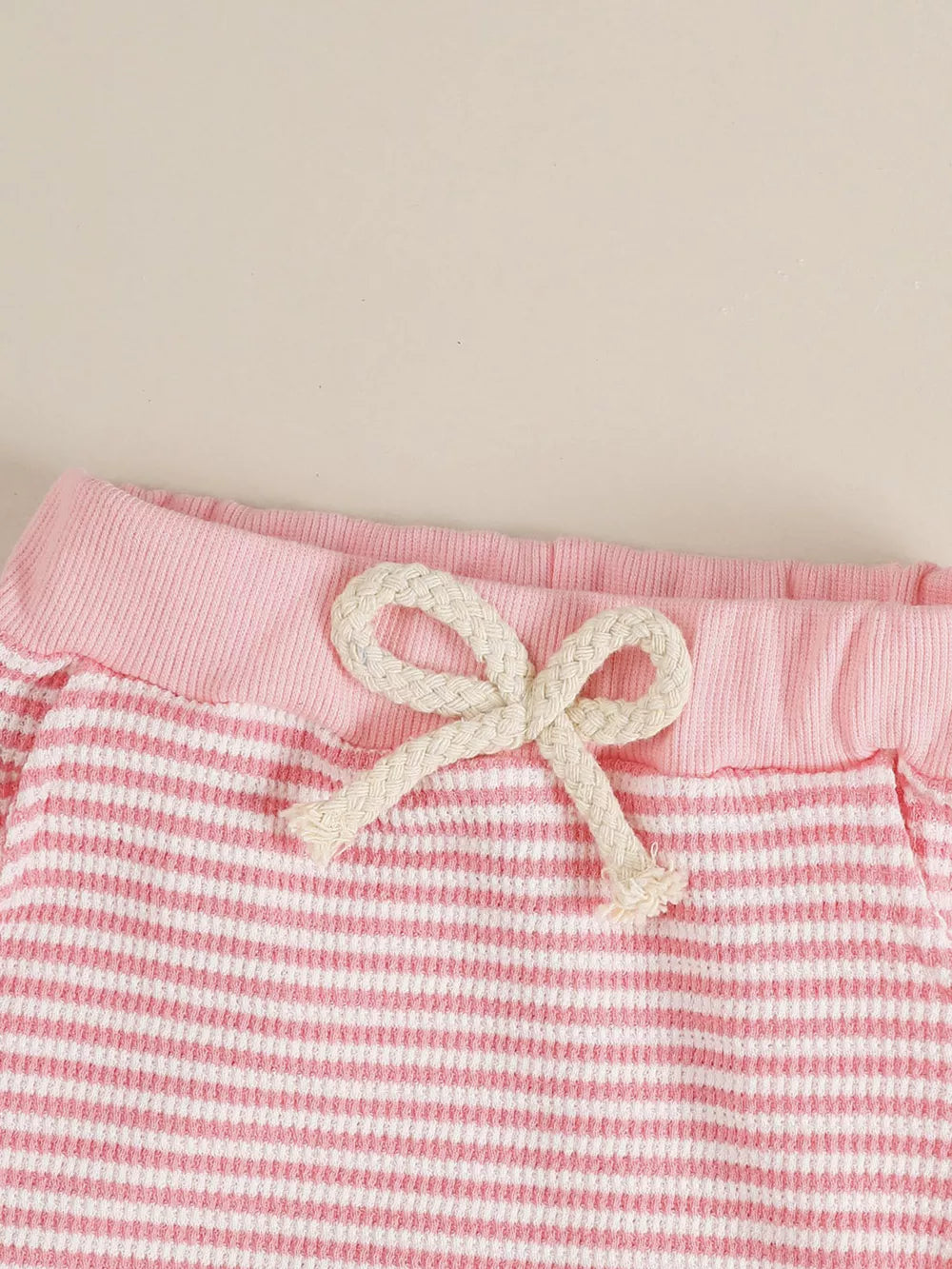 Pink and white striped baby shorts with a drawstring bow detail and ribbed waistband.