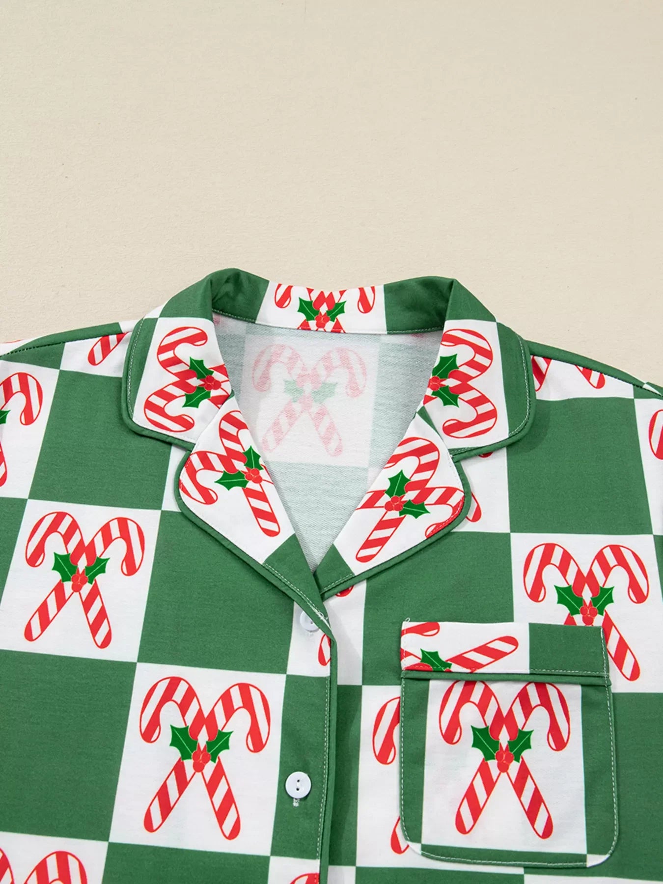 Green checkered pajama top with candy cane print, button front, and pocket detail.