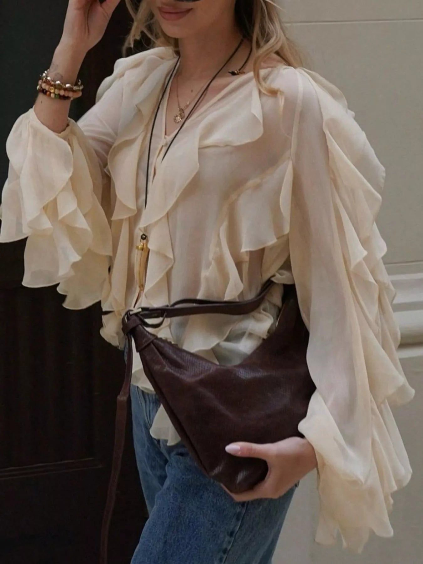Beige sheer long-sleeve blouse with cascading ruffles and a V-neckline.