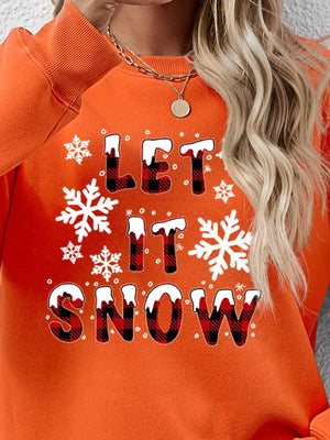 Orange crewneck sweatshirt with "Let It Snow" graphic, snowflakes, and buffalo plaid lettering.