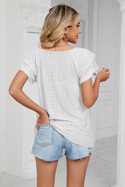 White eyelet knit blouse with flutter sleeves and V-neck, styled with denim shorts.