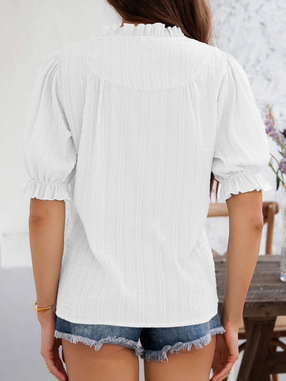 White textured puff sleeve blouse with ruffled neckline and cuffs.