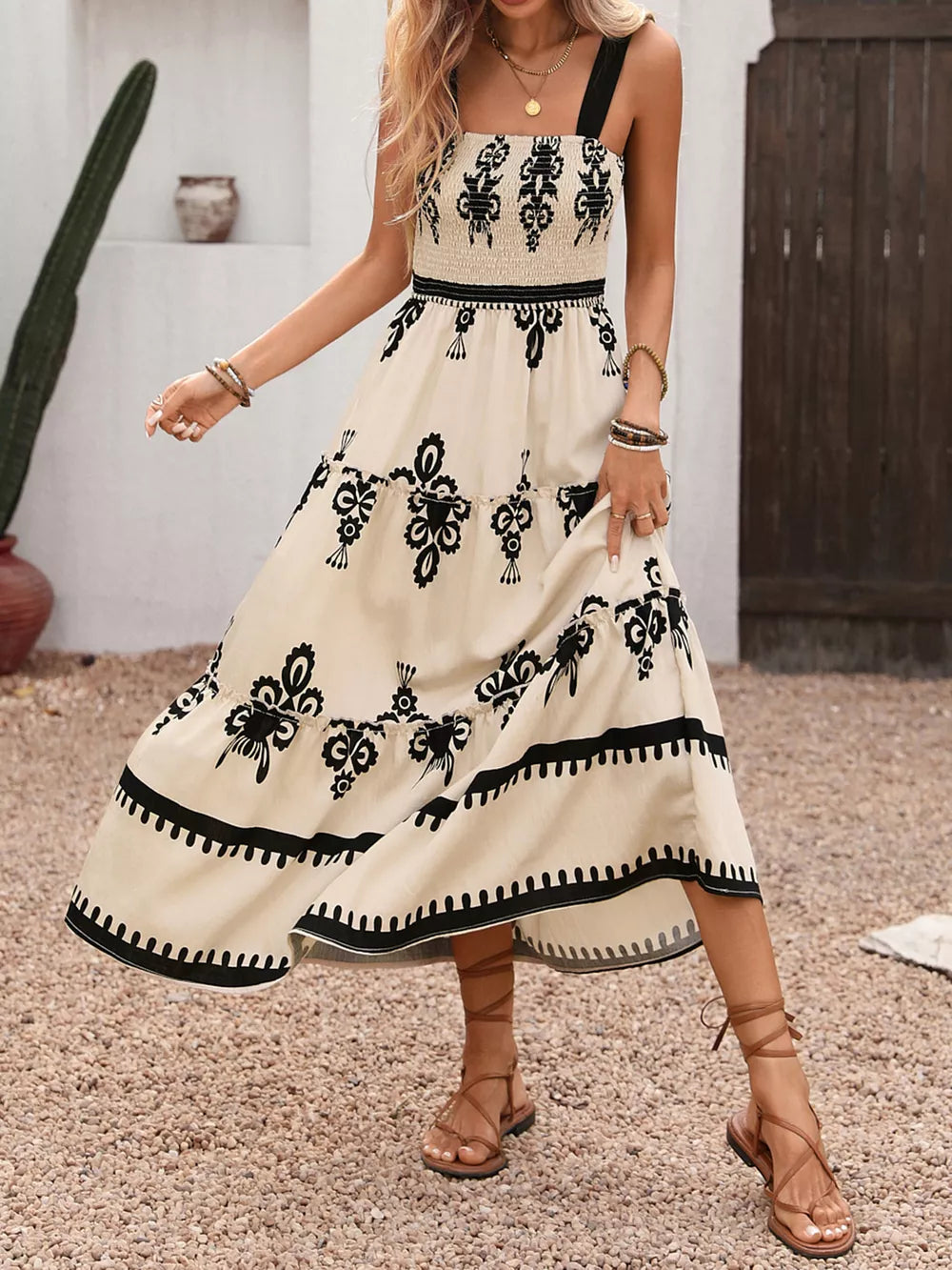 Bohemian cream maxi dress with black print, smocked bodice, tiered skirt, and black straps.