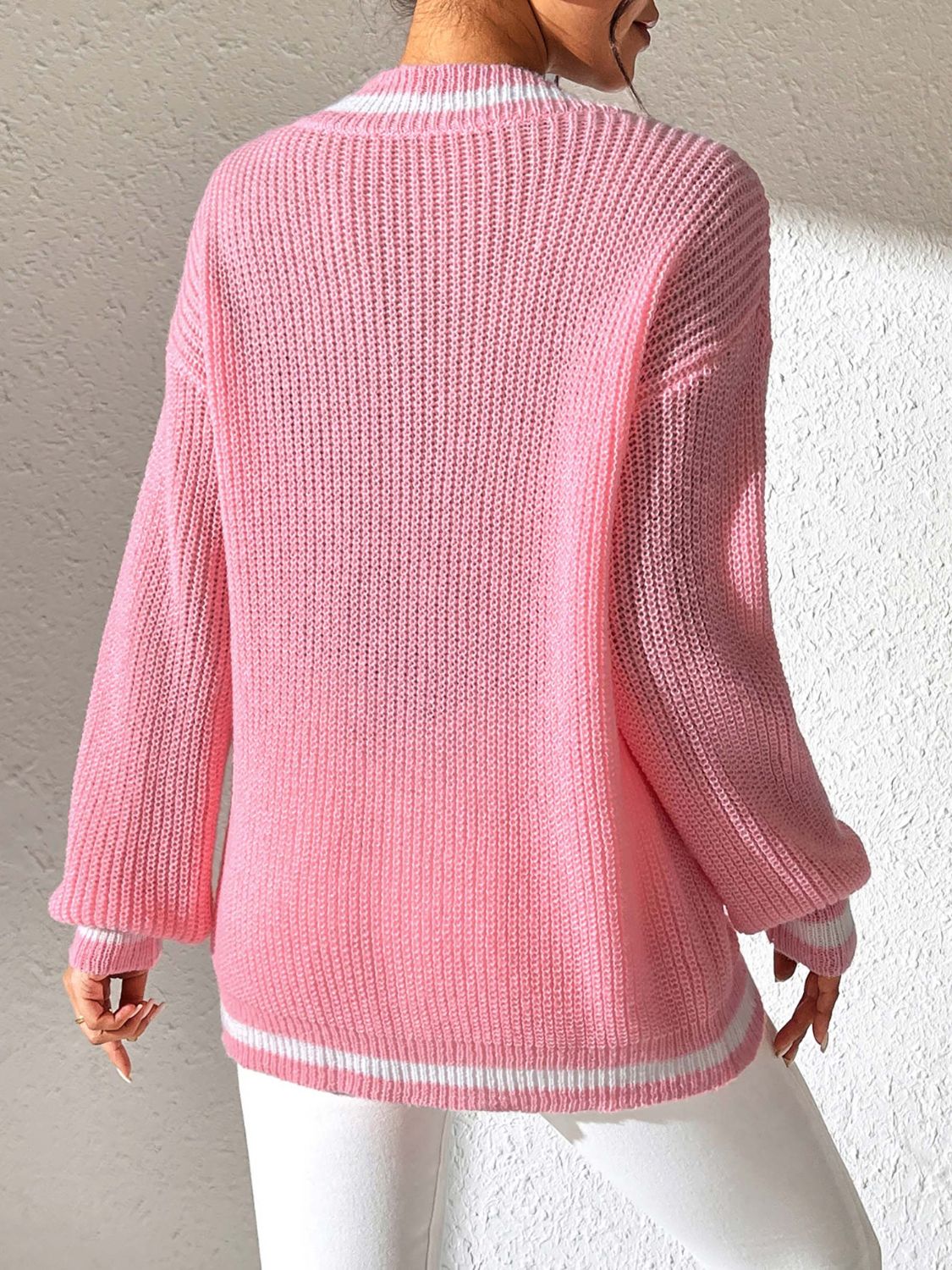 Dusty pink knit sweater with white striped V-neck and hem, long sleeves.