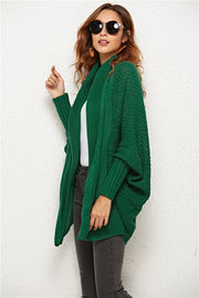 Textured cocoon knit cardigan in dark green with batwing sleeves and shawl collar.