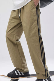 Khaki relaxed fit wide-leg sweatpants with black side stripes and drawstring waist.