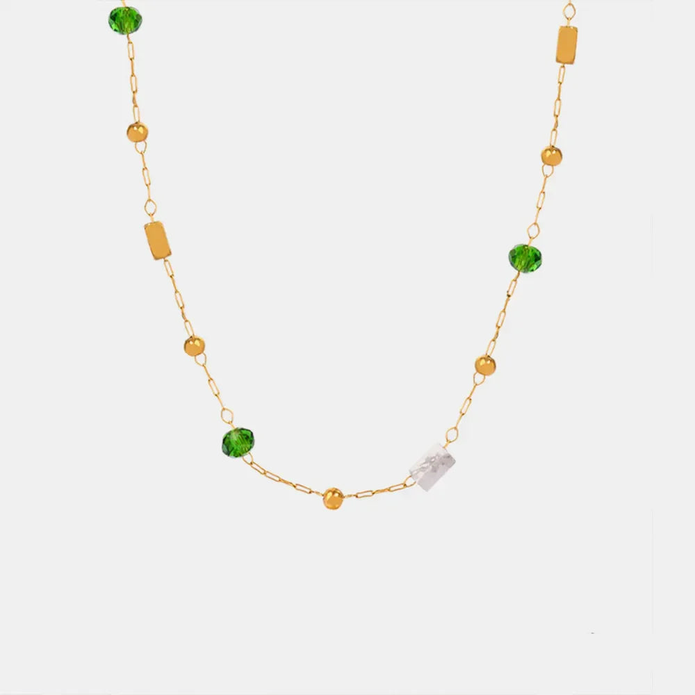 Gold layered necklace with green beads, gold spheres, and clear rectangular charms.