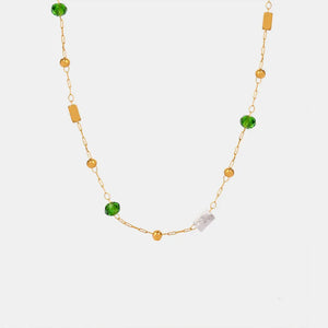 Gold layered necklace with green beads, gold spheres, and clear rectangular charms.