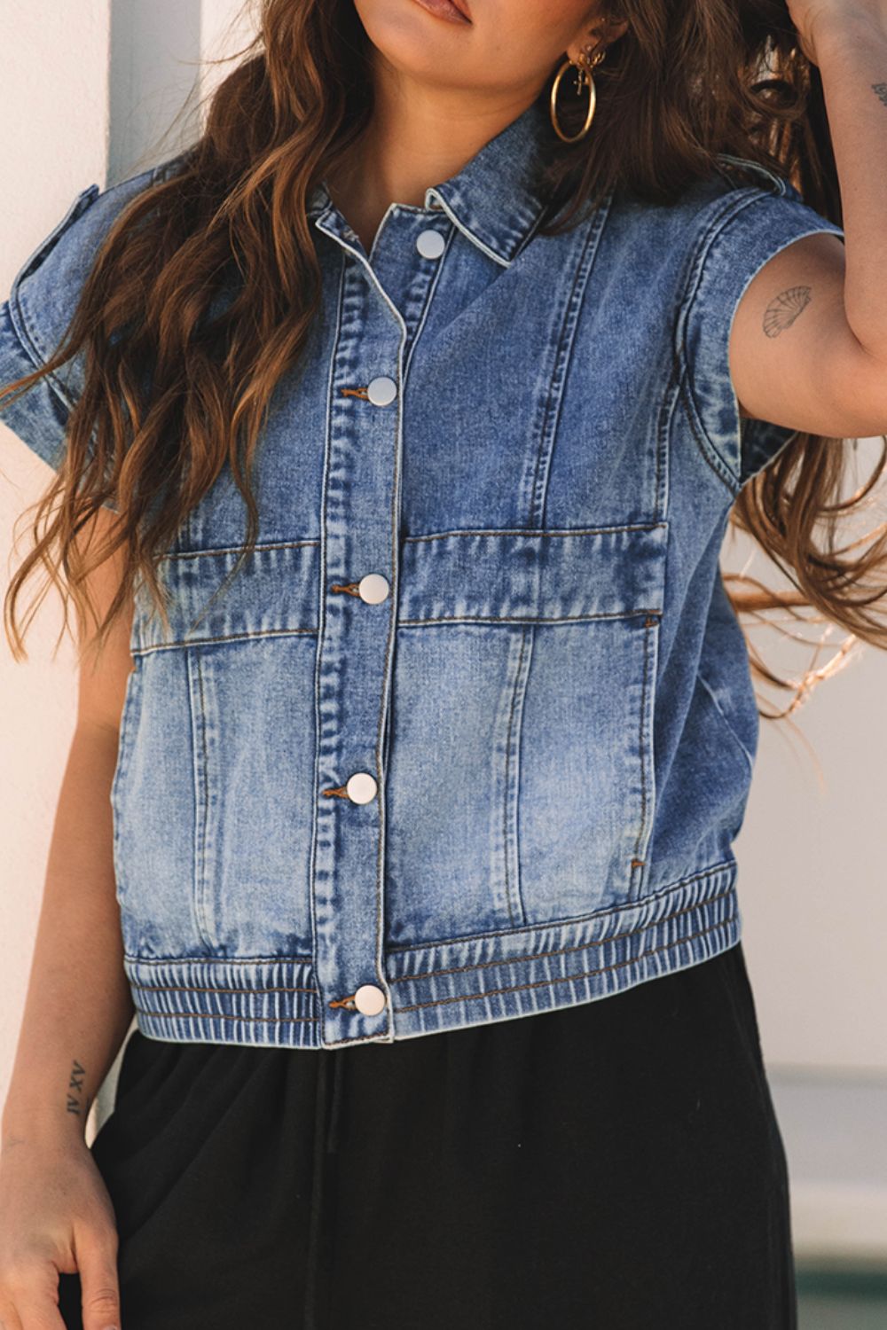 Boxy denim vest in medium wash with button front, chest pockets, and shoulder detail.