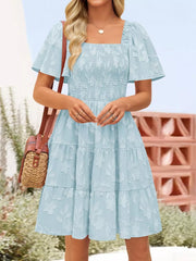 Light blue smocked mini dress with tiered skirt and floral texture.