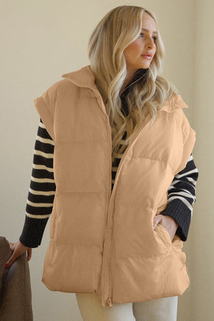 Tan padded sleeveless hooded vest with zip front and pockets, worn over striped sweater.