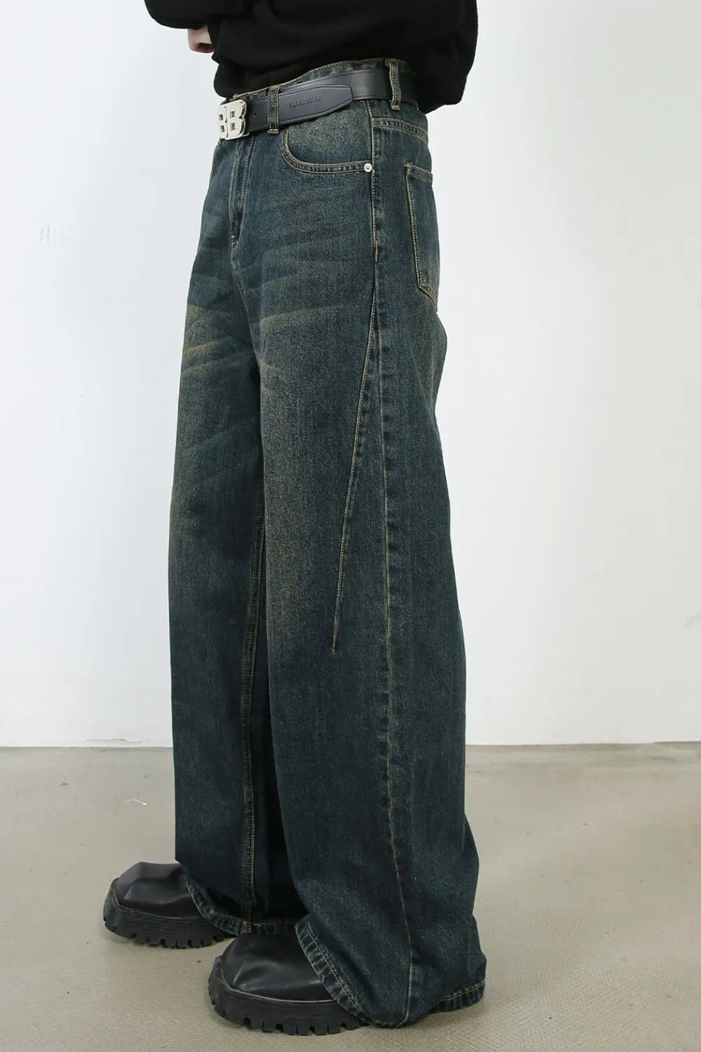Faded dark denim wide-leg trousers with a relaxed fit and visible stitching detail.