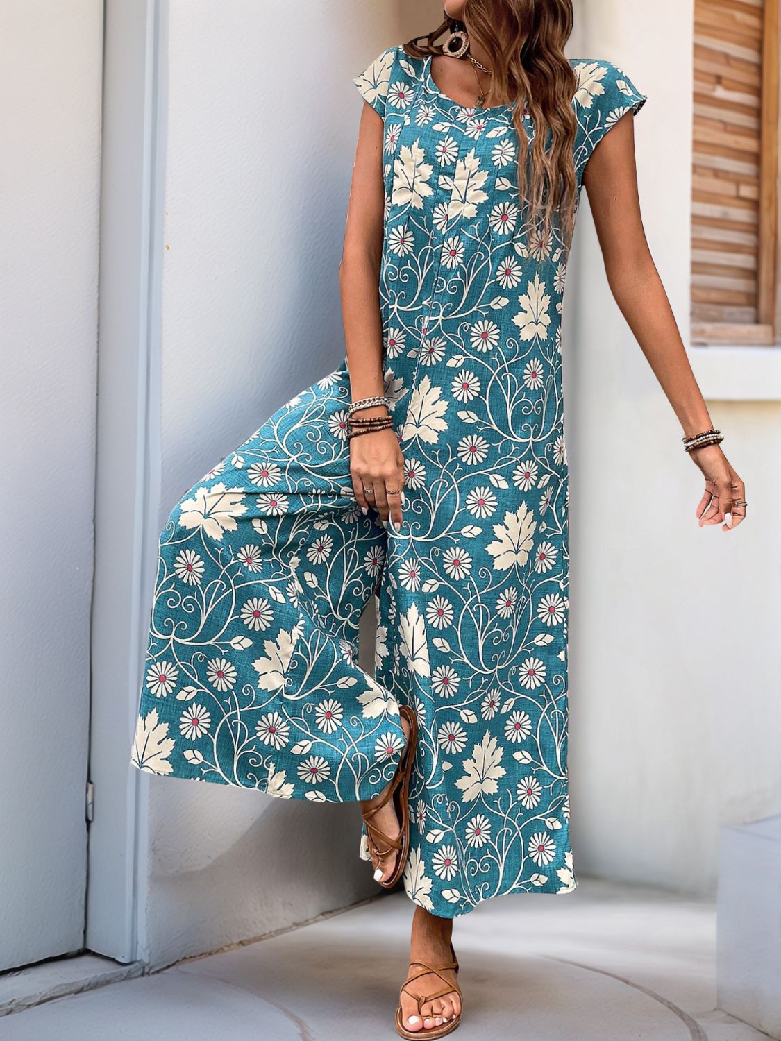 Botanical print culotte jumpsuit in dark green with short sleeves and wide legs.