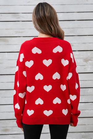 Red acrylic sweater with allover white intarsia hearts pattern.