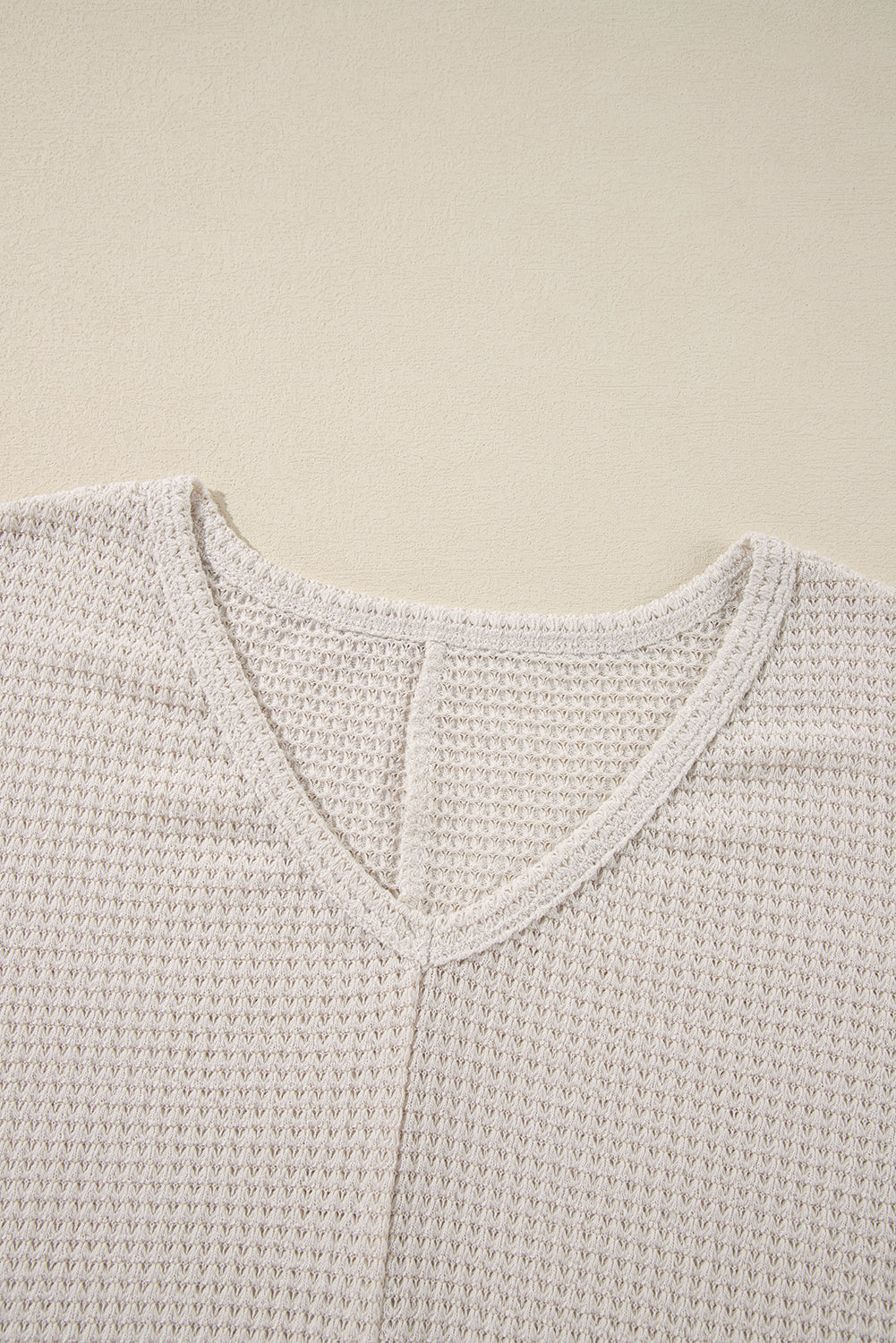 Beige waffle knit V-neck top with a subtle slit detail at the neckline.