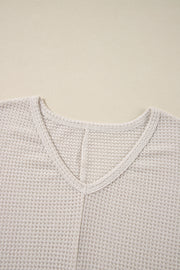 Beige waffle knit V-neck top with a subtle slit detail at the neckline.