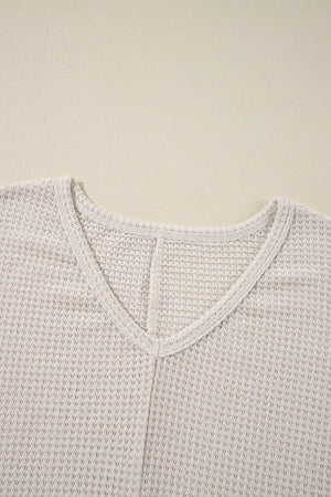Beige waffle knit V-neck top with a subtle slit detail at the neckline.