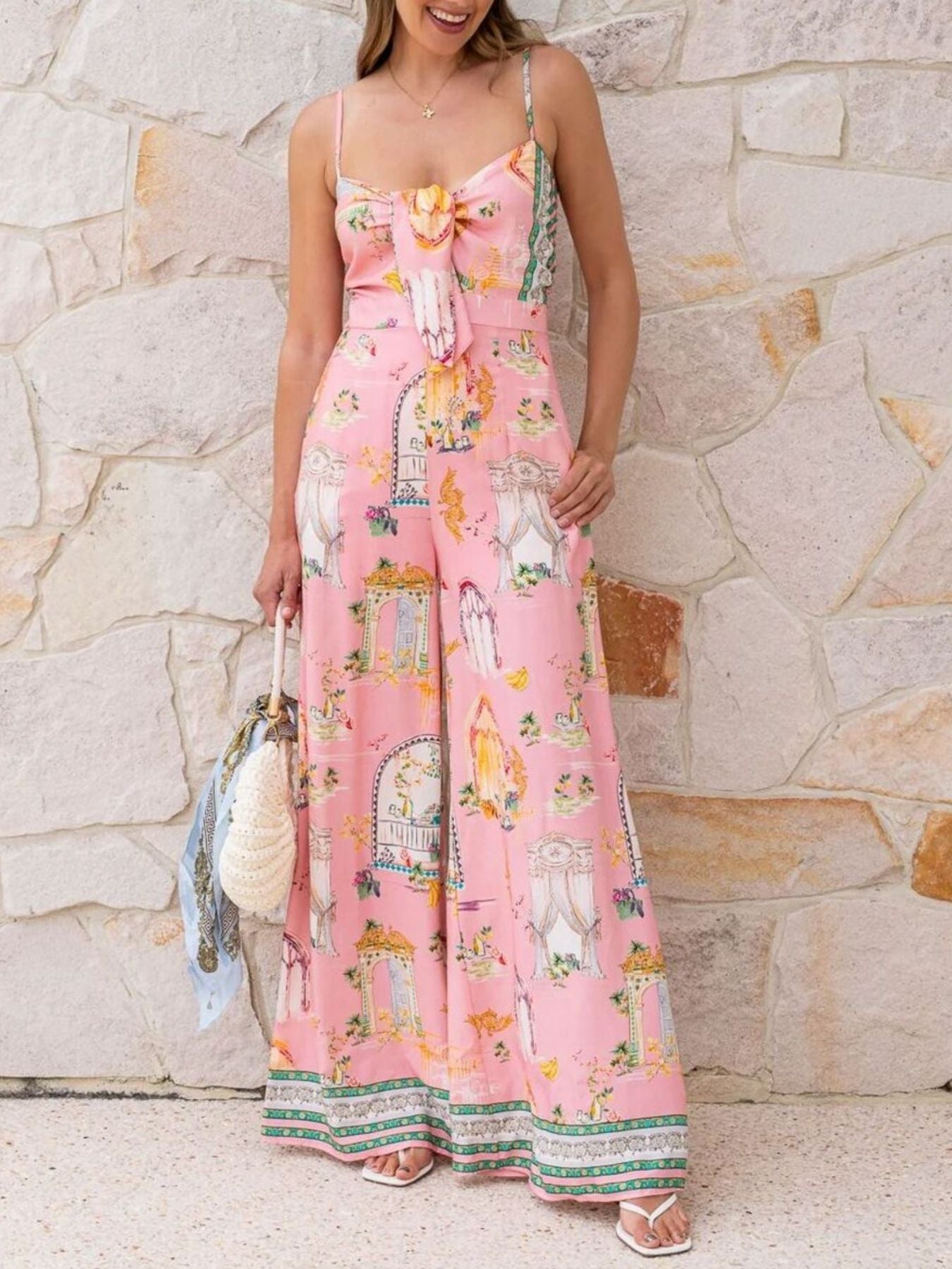 Pink architectural print tie-front wide-leg jumpsuit with bow detail and spaghetti straps.