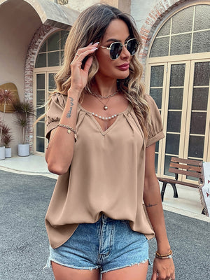 Camel gathered sleeve blouse with plunge neckline and pearl trim, styled with denim shorts.