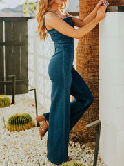 Denim jumpsuit with notched V-neck, wide legs, and contrast stitching.