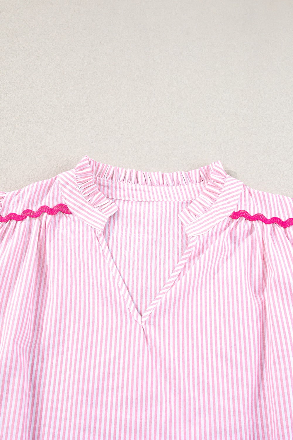 Blush pink and white striped blouse with ruffled neckline and scalloped trim detail.
