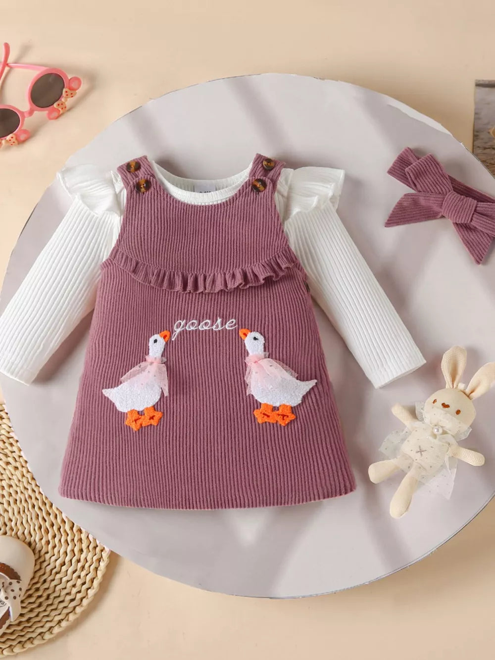 Plum purple corduroy baby dress with ruffled neckline, goose applique, and white long-sleeve bodysuit.