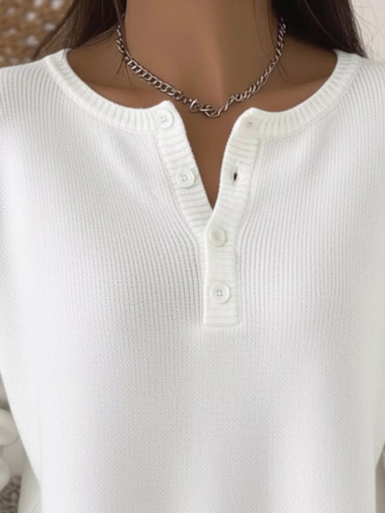 White knit long-sleeve top with button detail at the neckline.