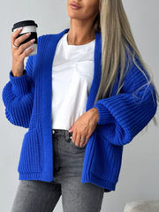 Royal blue textured knit cardigan with puff sleeves and pockets, worn open over a white t-shirt.