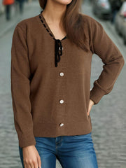 Brown knit cardigan with ribbon trim, black tie detail, and pearl buttons.