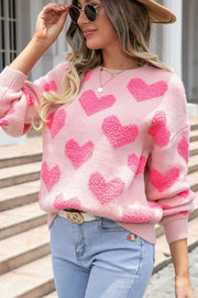 Blush pink knit sweater with textured heart pattern, crew neck, and long sleeves.