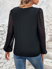 Black blouse with sheer dot puff sleeves and V-neck.