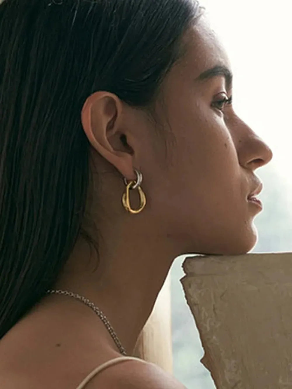 Two-tone sculptural asymmetric hoop earrings in gold and silver, 18K gold-plated.