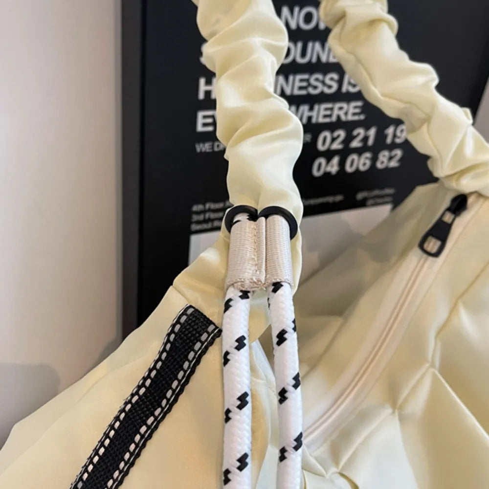 Ivory ruched handle crescent bag with rope strap detail and black trim.