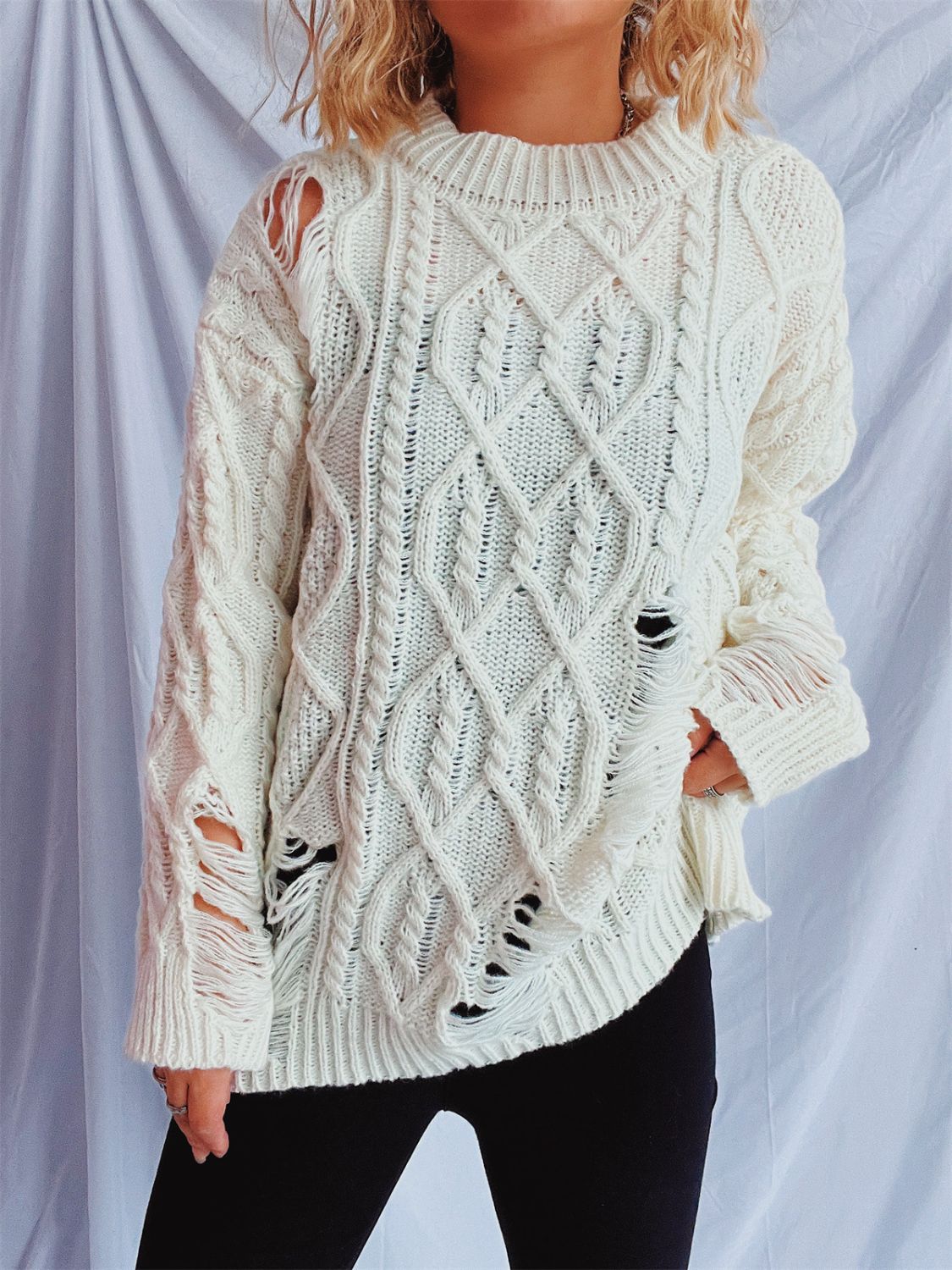 White distressed cable knit sweater with ripped details and a crew neckline.