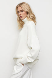 Oversized white turtleneck knit sweater with ribbed cuffs and hem.
