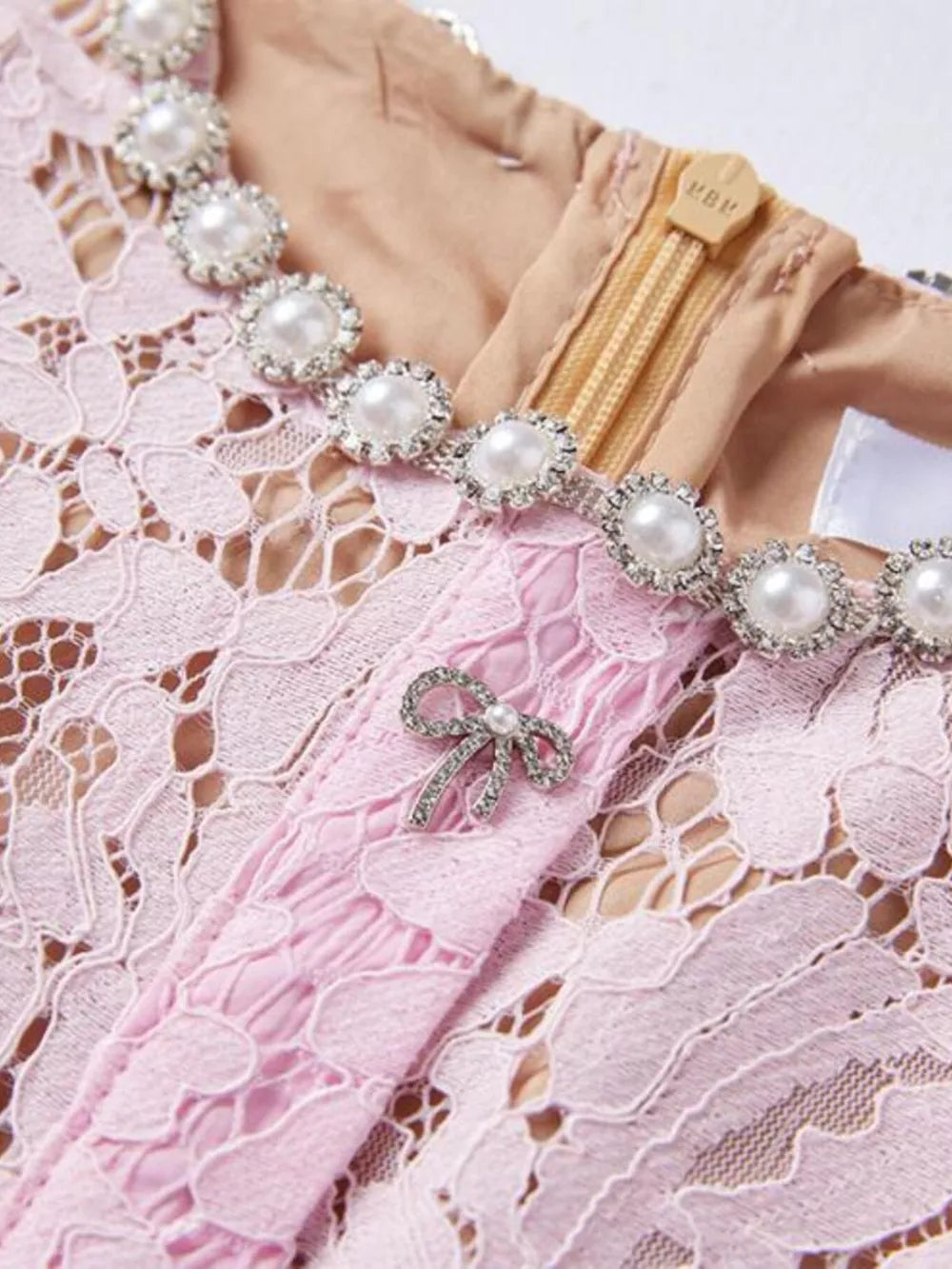 Powder lace dress with pearl and rhinestone neckline detail and bow brooch.