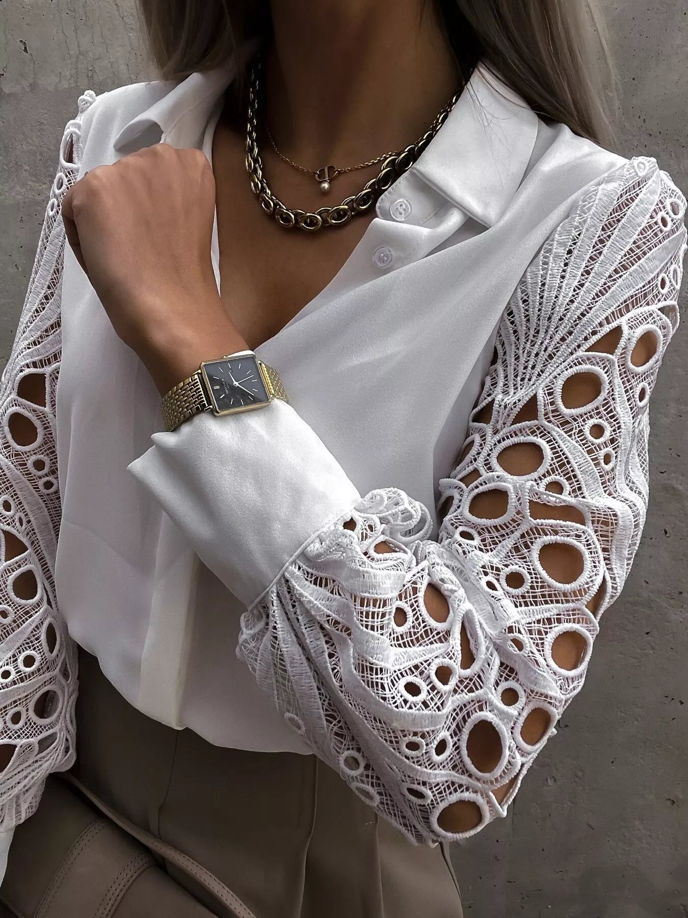 White collared blouse with intricate lace sleeves and buttoned cuffs.