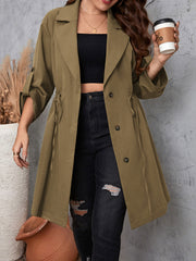 Olive green trench coat with gathered waistline, roll-up sleeves, and tie detail.
