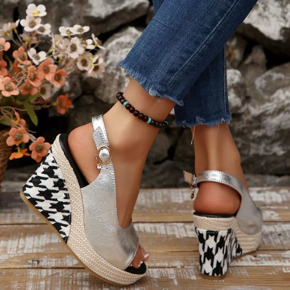 Sleek silver open-toe wedge sandals with decorative buckle and houndstooth wedge detail.