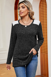 Black ribbed knit top with eyelet shoulder detail and crew neck.