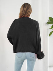 Black acrylic knit cardigan with balloon sleeves and floral appliqué detail on the cuff.