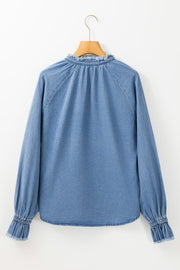 Light blue denim blouse with ruffled collar and cuffs, long sleeves.