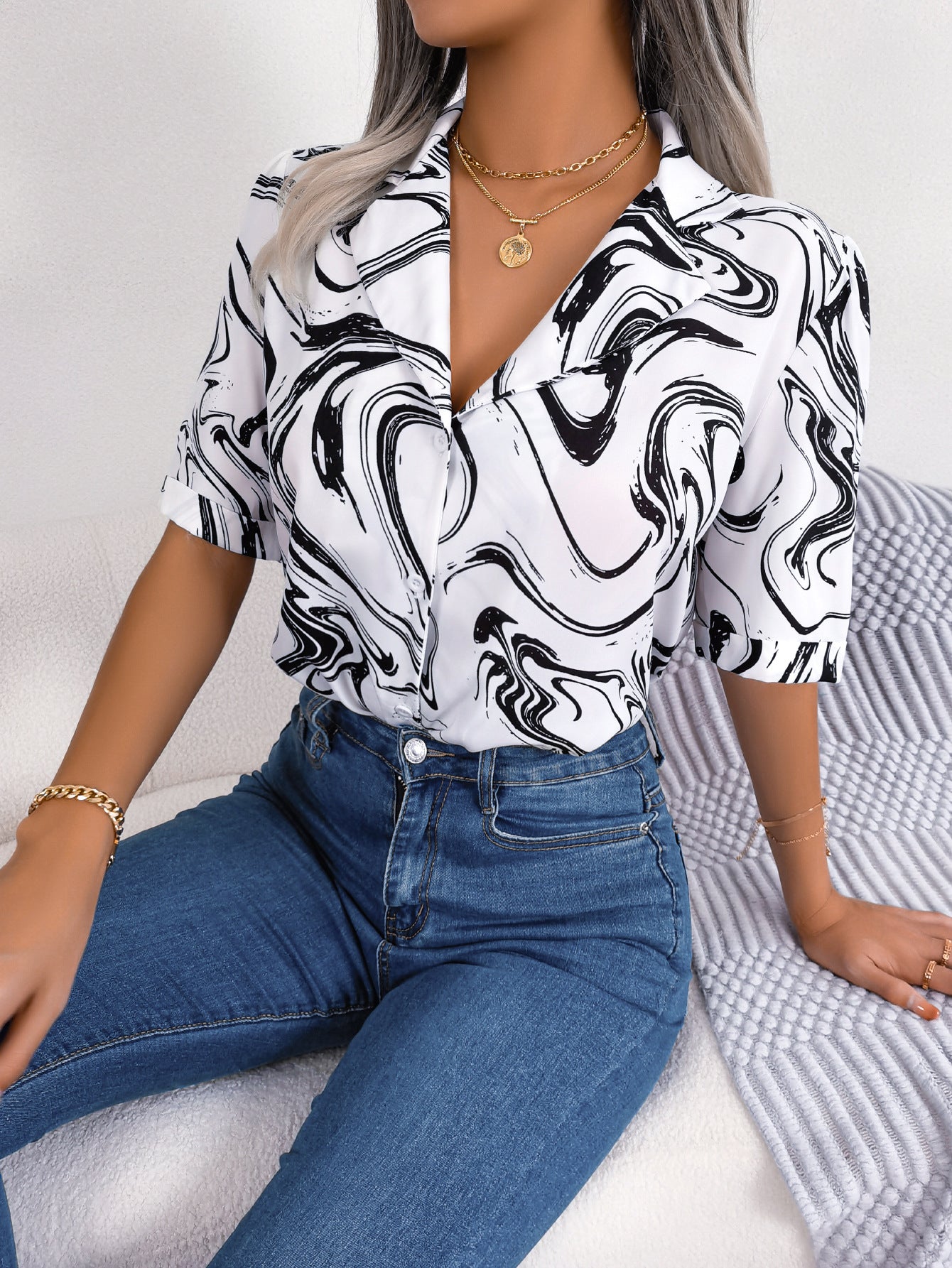 White blouse with black swirl print, camp collar, short sleeves, and button front.