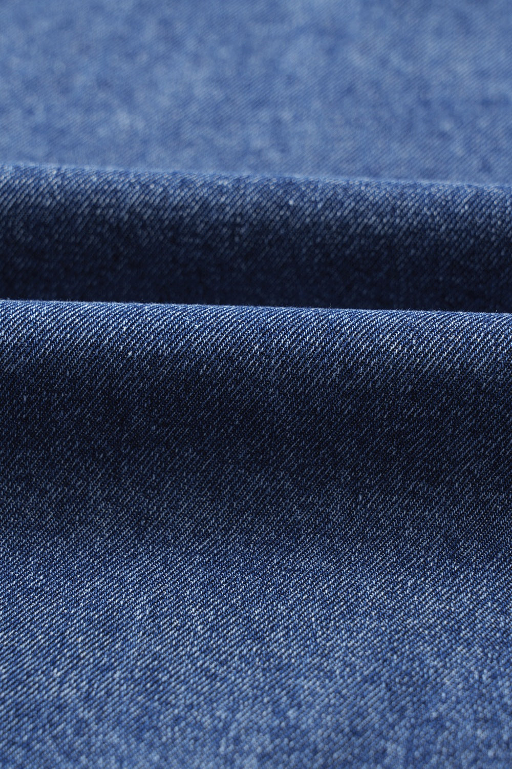 Utility denim mini dress in medium blue, showing fabric texture and folds.