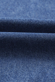 Utility denim mini dress in medium blue, showing fabric texture and folds.