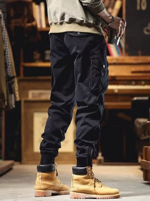 Men's black cargo joggers with drawstring and cuffed ankles, styled with boots.