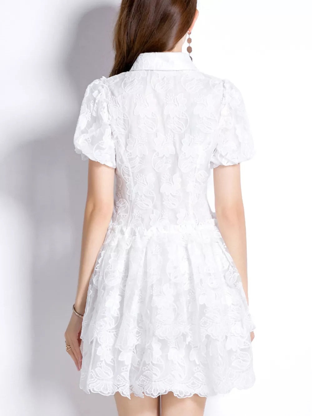 White lace mini dress with puff sleeves and tiered skirt.
