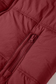 Burgundy quilted puffer vest detail showing a zippered pocket and stitching.