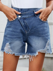 Dusty blue denim shorts with asymmetric waistline, distressed details, and frayed hem.